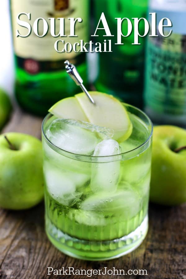 Sour Apple Cocktail above a green cocktail surrounded by apples