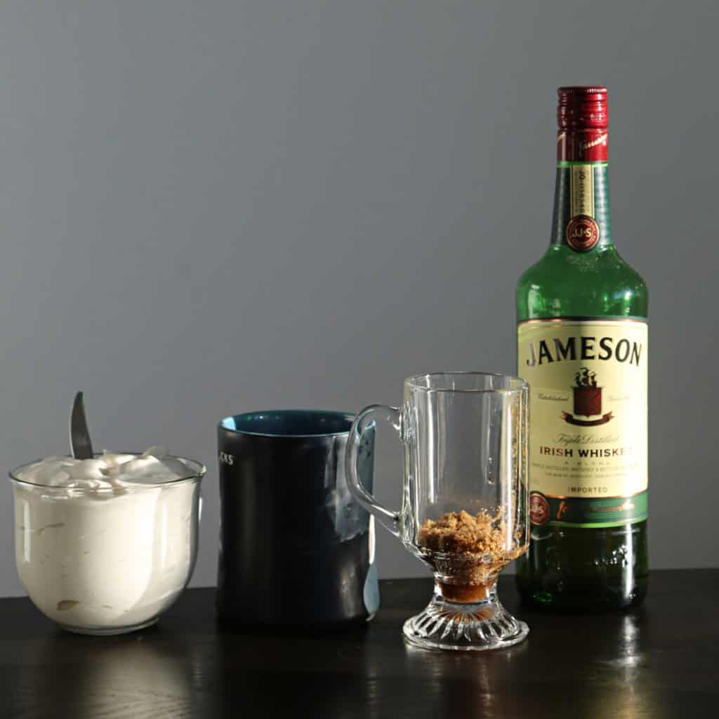 Ingredients/supplies needed to make Irish Coffee including Jameson Irish Whiskey, Whipped Cream, coffee Cup and Brown Sugar