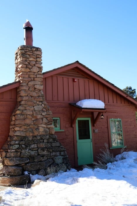 red cabin with stone fireplace and green door 