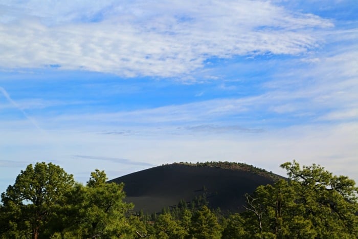 Scenic view of Sunset Crater Volcano with a blue sky and white clouds. 