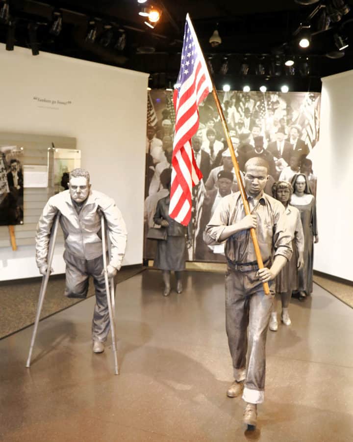 two statues of people marching with an American Flag in the Selma to Montgomery interpretative Center