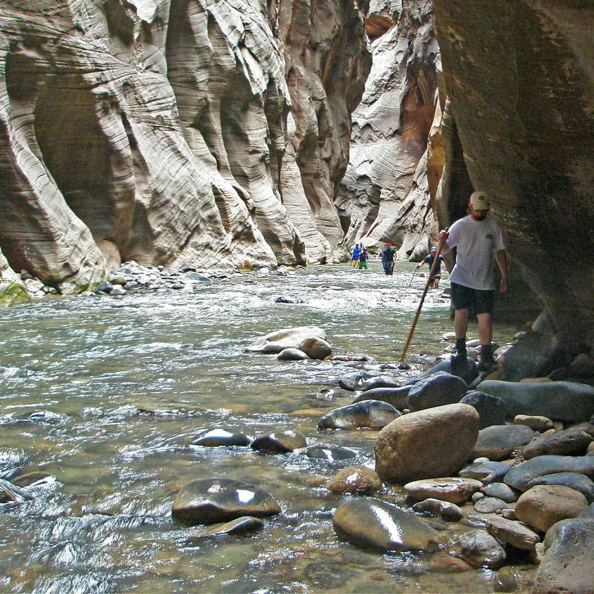 People hiking in the Zion Narrows as the walls are getting closer and taller.