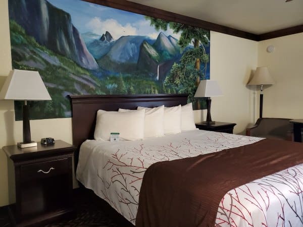 King bed with mural of Yosemite behind it at the Best Western Plus Oakhurst Yosemite