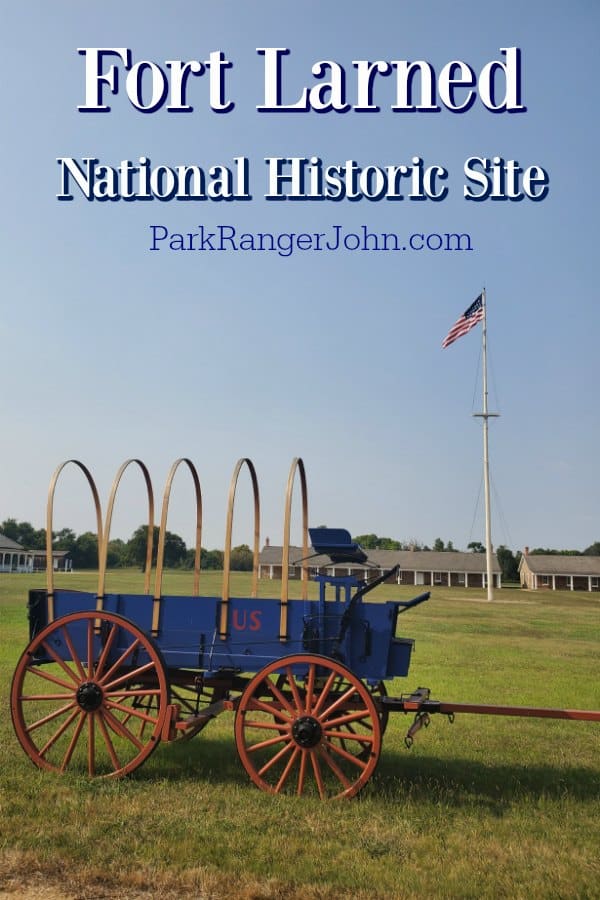Fort Larned National Historic Site over a blue historic wagon and american flag