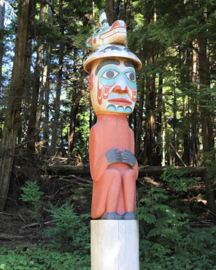 Man wearing bear hat totem pole at Totem Bight State Historical Park in Ketchikan Alaska