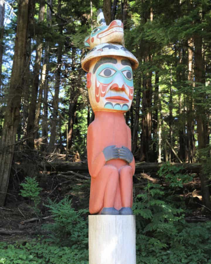 Man wearing bear hat totem pole at Totem Bight State Historical Park in Ketchikan Alaska