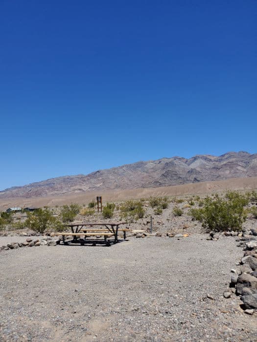 picnic table in a gravel campsite with mountains in the background