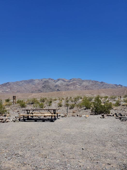 campsite with picnic table on gravel campsite with mountains in the background