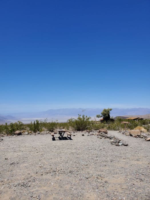 Gravel campsite with picnic table and mountains in the background