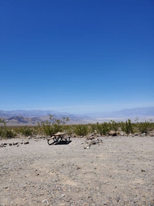 gravel campsites with picnic table and view of the mountains in the background