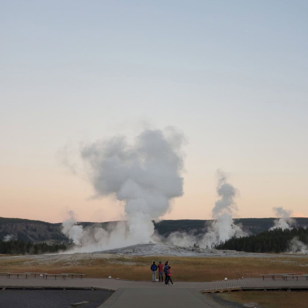 Visitors standing in front of Old Faithfful in Yellowstone