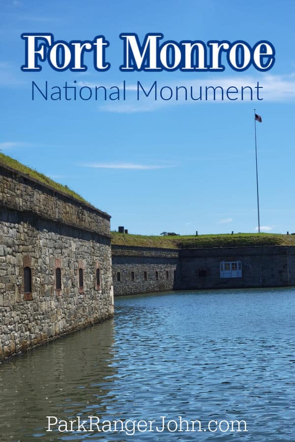 Fort Monroe National Monument text over a moat of water and historic fort walls with an American flag