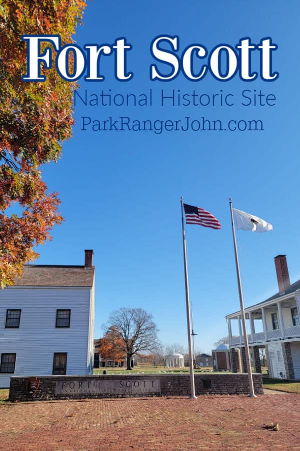 Fort Scott National Historic Site text printed over the entrance to the park with historic buildings and flag poles