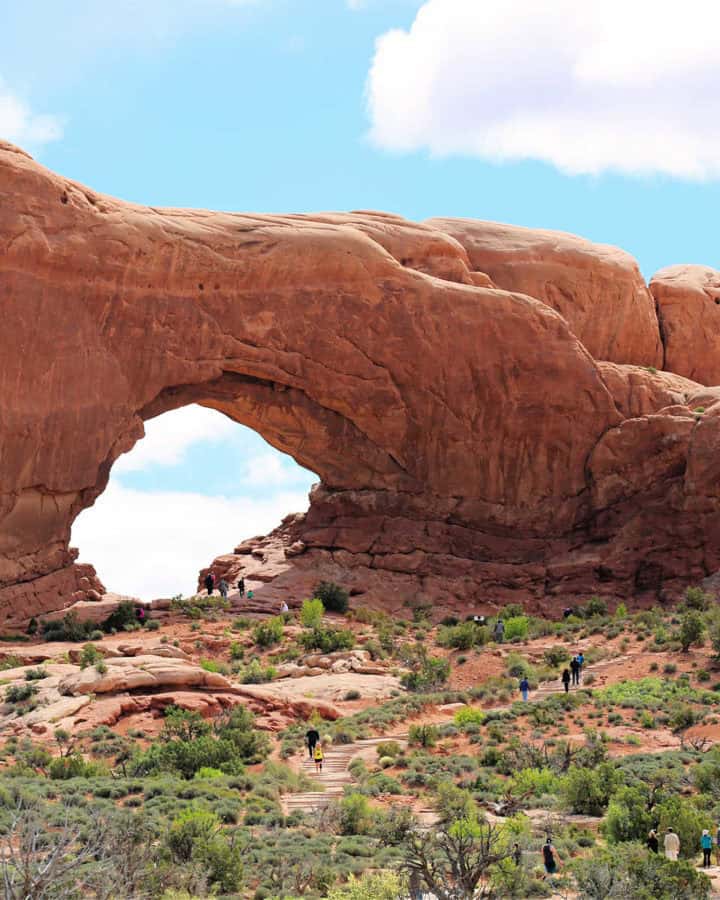 Photo of Double Arch in the Windows swction of Arches National Park with visitors hiking to the base of the Arch