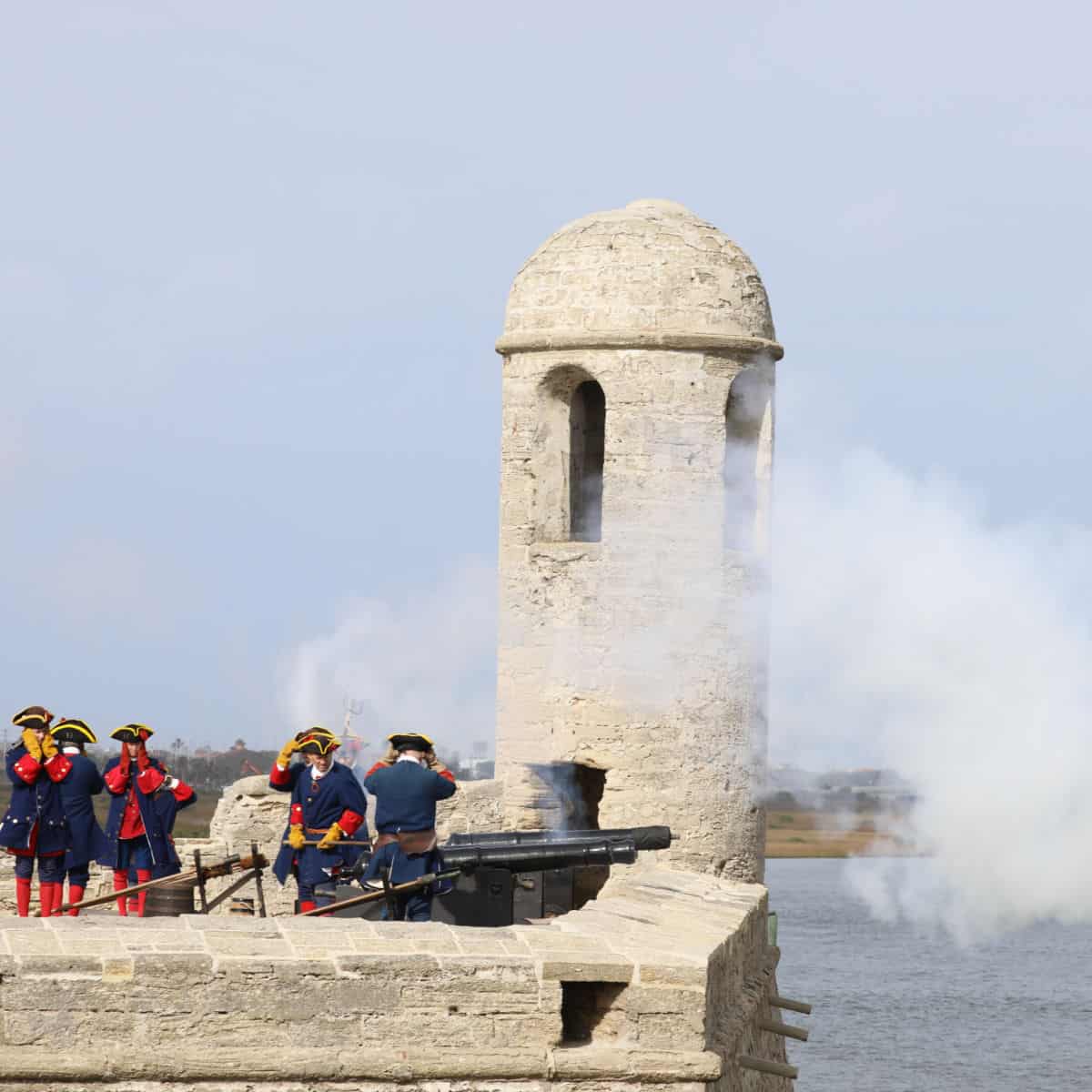 Cannon being fired off of Castillo De San Marcos with interpreters in period costumes.