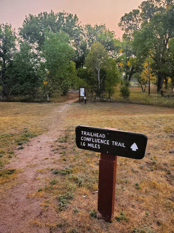 Confluence Trail sign, path leading towards trees in Fort Laramie National Historic Site