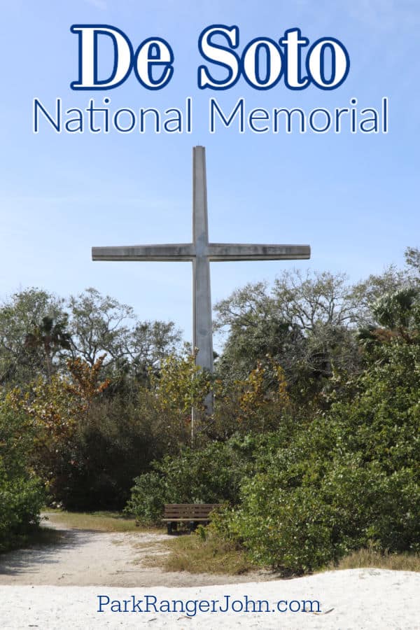 De Soto National Memorial text printed over a large cross surrounded by plants and sand