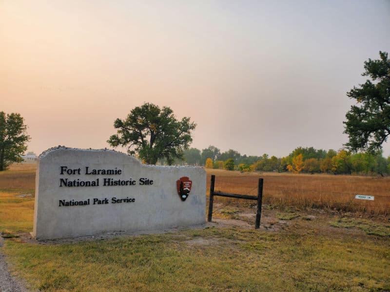 Fort Laramie National Historic Site entrance sign with a brown field near it. 