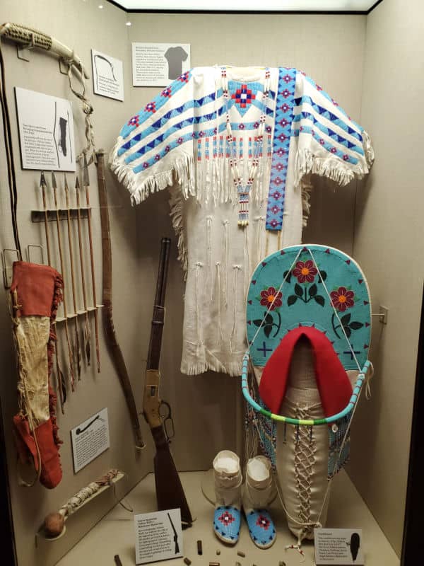 Beaded tunic, moccasins, and baby board with weapons in a display at Big Hole National Battlefield