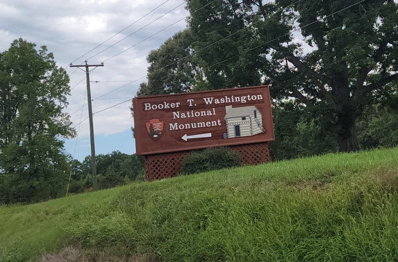 Booker T Washington National Monument entrance sign on a grassy hill