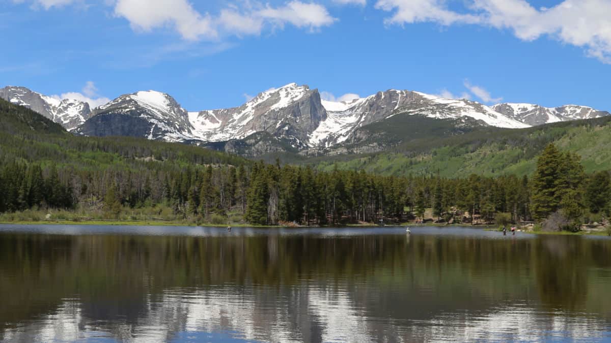 Rocky Mountains over Sprague Lake with fisherman in the lake