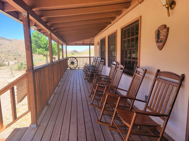 Wooden rocking chairs lined up on the front porch of the Fort Bowie NHS Visitor Center