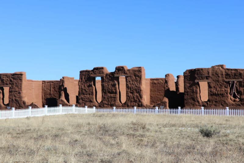 historic adobe wall ruins with a white fence in Fort Union National Monument