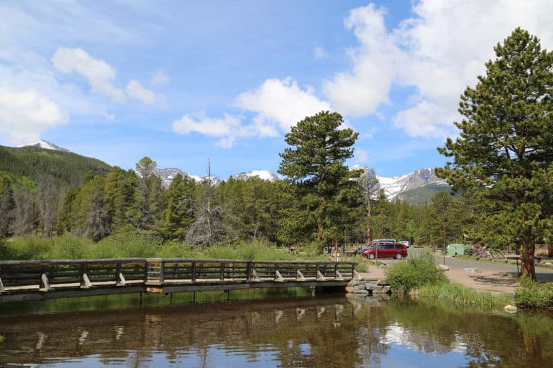 Bridge over water with the Rocky Mountains in the background on the Sprague Lake Trail