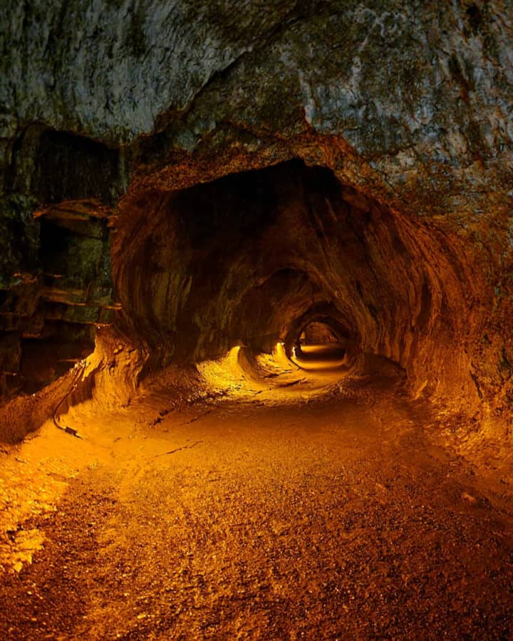 Nahuku Thurston Lava Tube lit by lights showing the trail through the lava tube