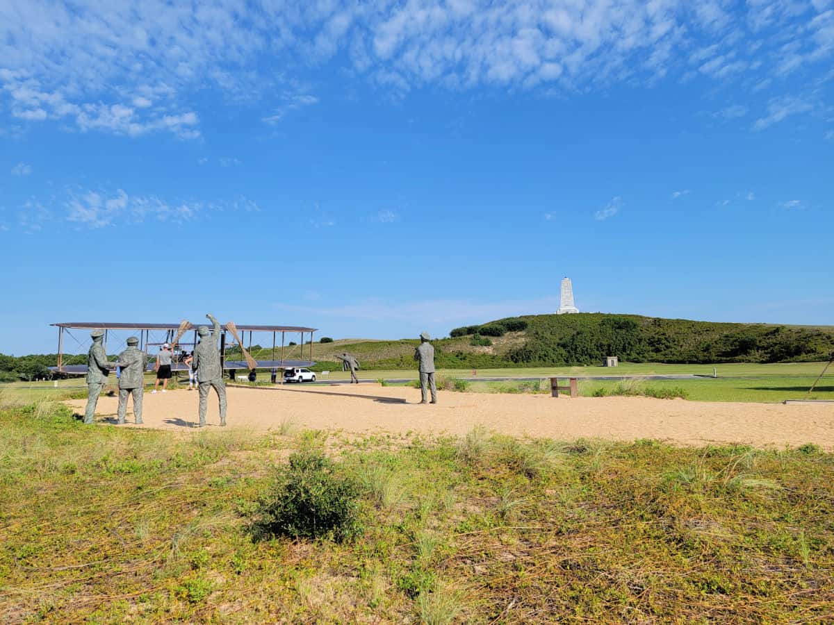 airplane sculpture and the Wright Brothers National memorial on a hill
