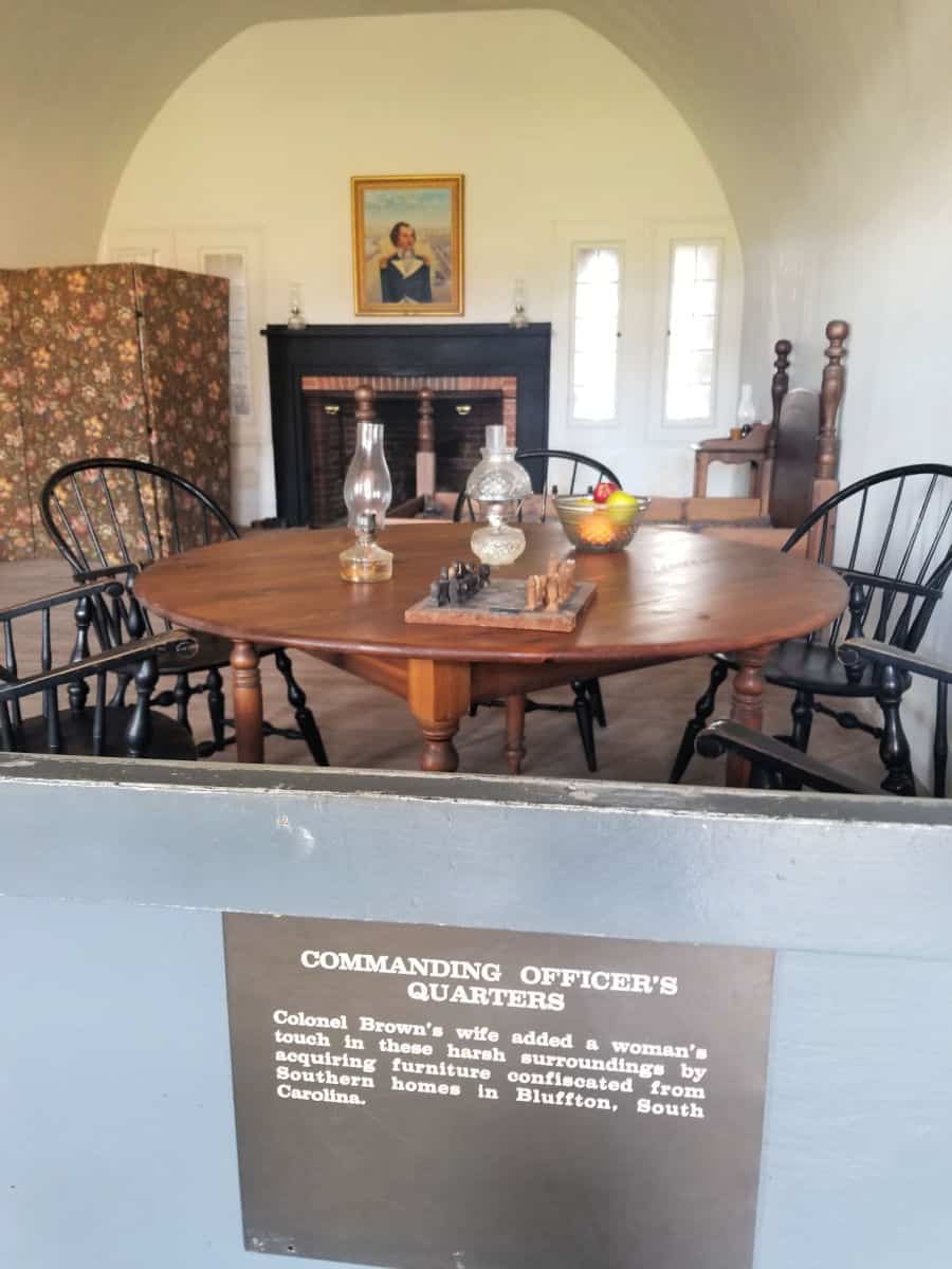 Commanding Officer's Quarters sign in front o f a dining room table set with glass lamps and a fireplace