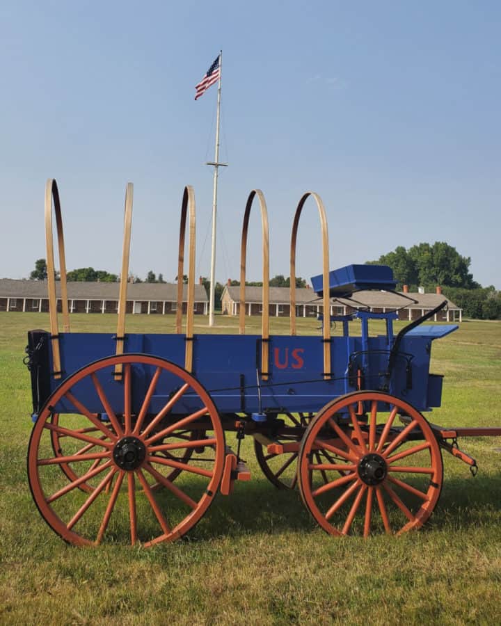 Historic horse drawn wagon by a flag pole on the grounds of Fort Larned NHS