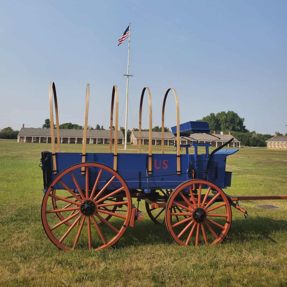 Historic horse drawn wagon by a flag pole on the grounds of Fort Larned NHS