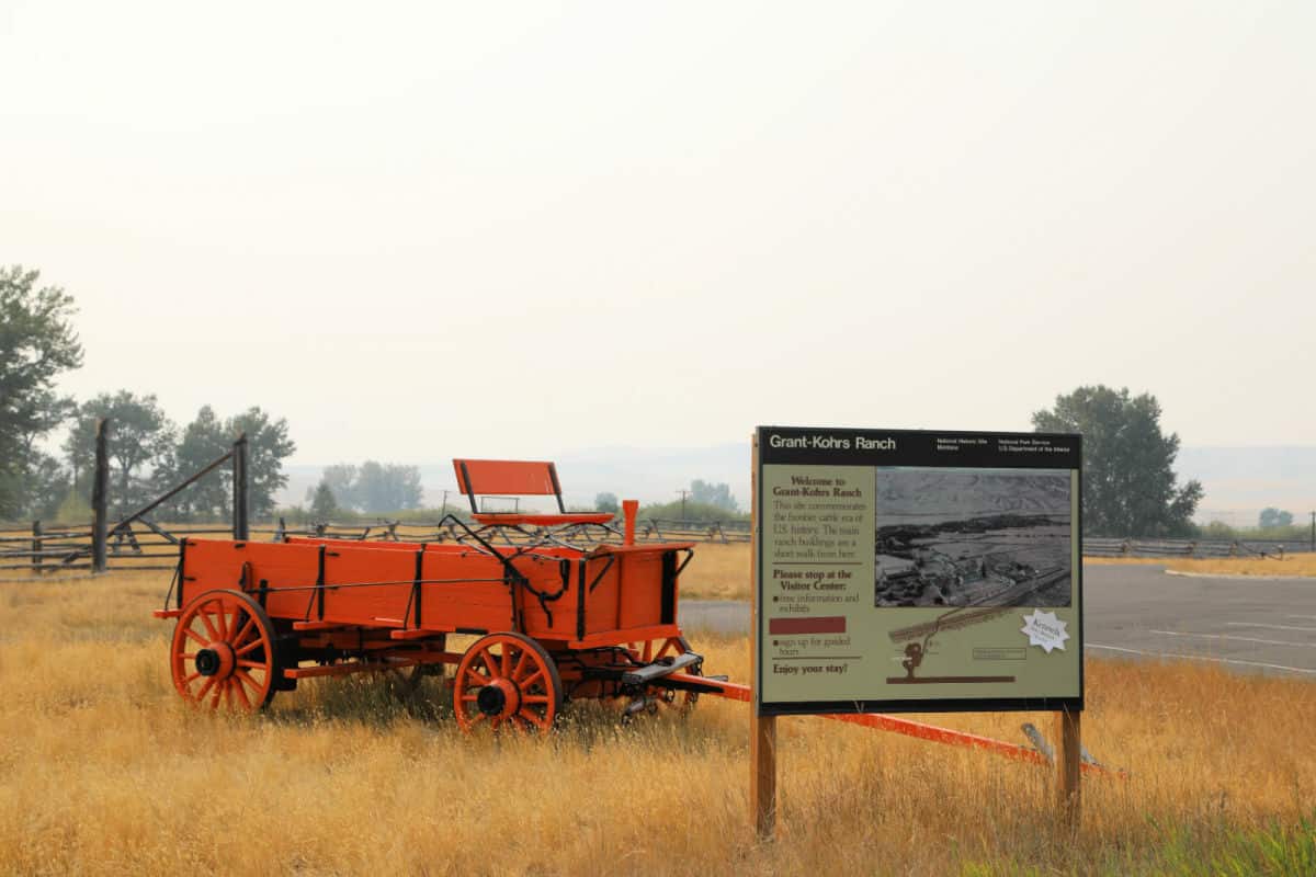 Historic red wagon behind a Grant-Kohrs Ranch bulletin Board