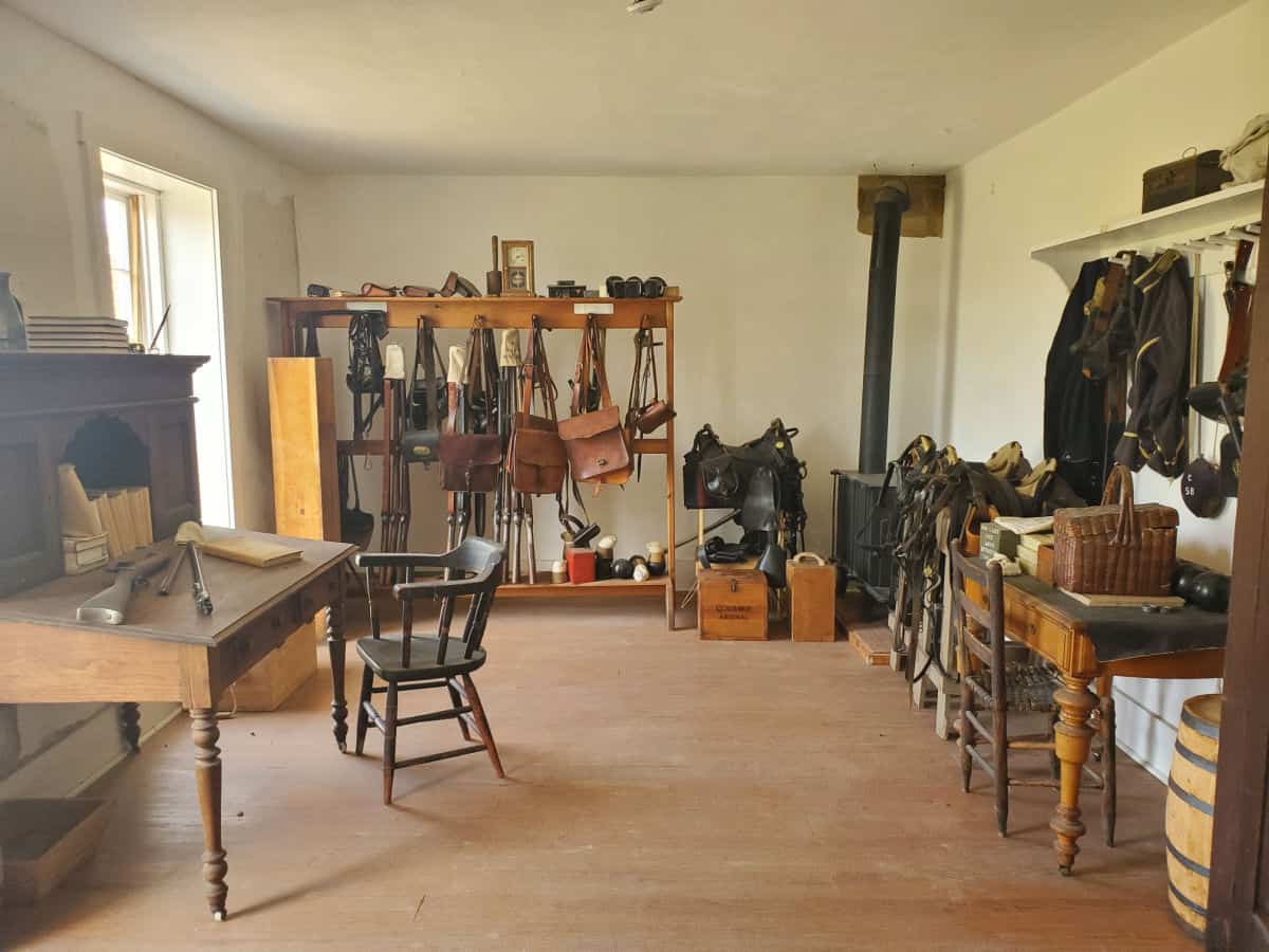 Storage area with a saddle, messenger bags, and gear by a wooden desk