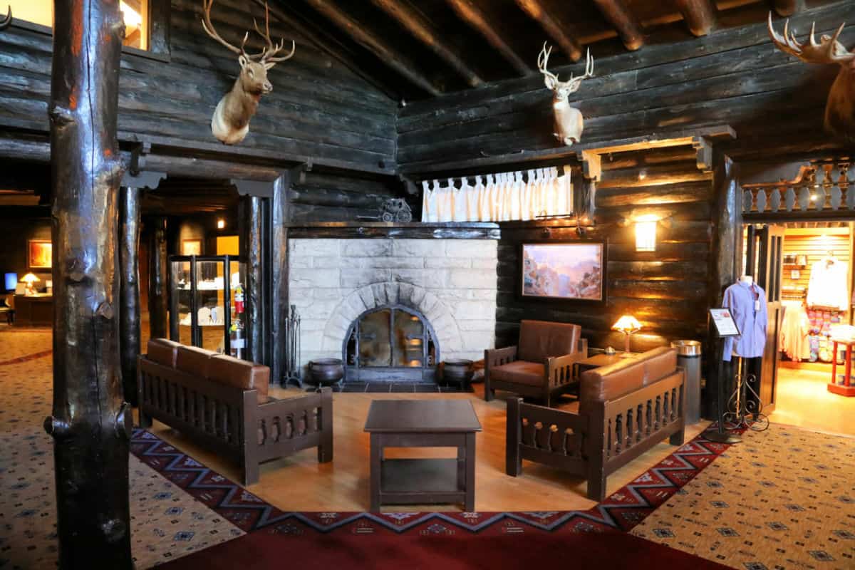 deer heads on the wood walls over a stone fireplace with couches and the el tovar hotel gift shop