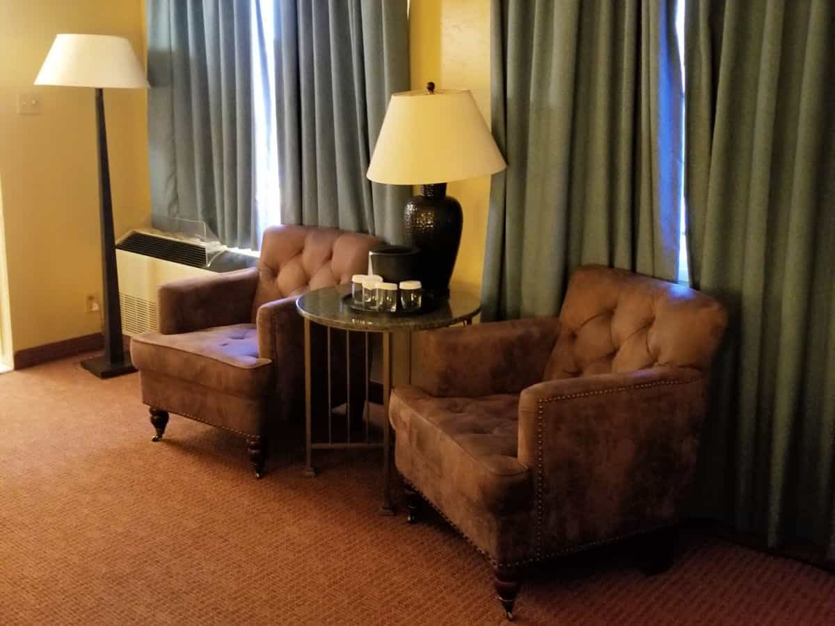 Two chairs next to a table with a lamp and glasses