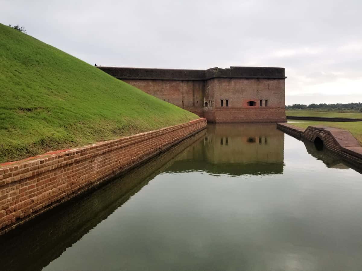 Moat surrounding Fort Pulaski with grass hill and brick fort