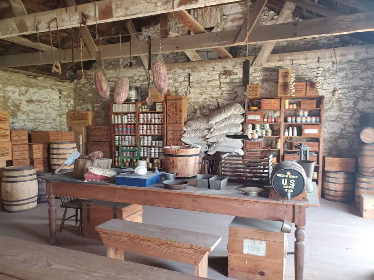 Commissary building with meat hanging, and shelves filled with products by a table