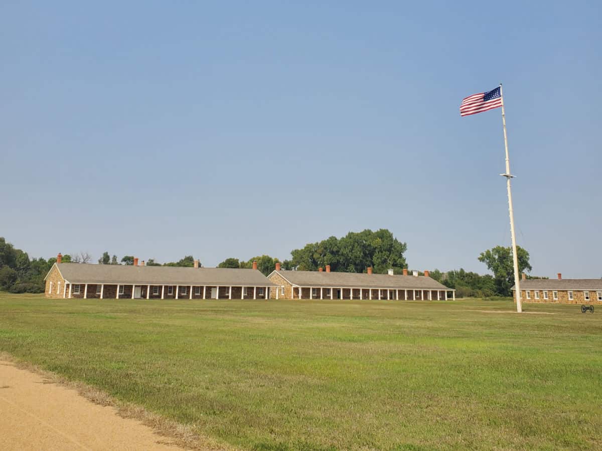 Parade grounds with a US Flag and Pole and Fort Larned historic buildings