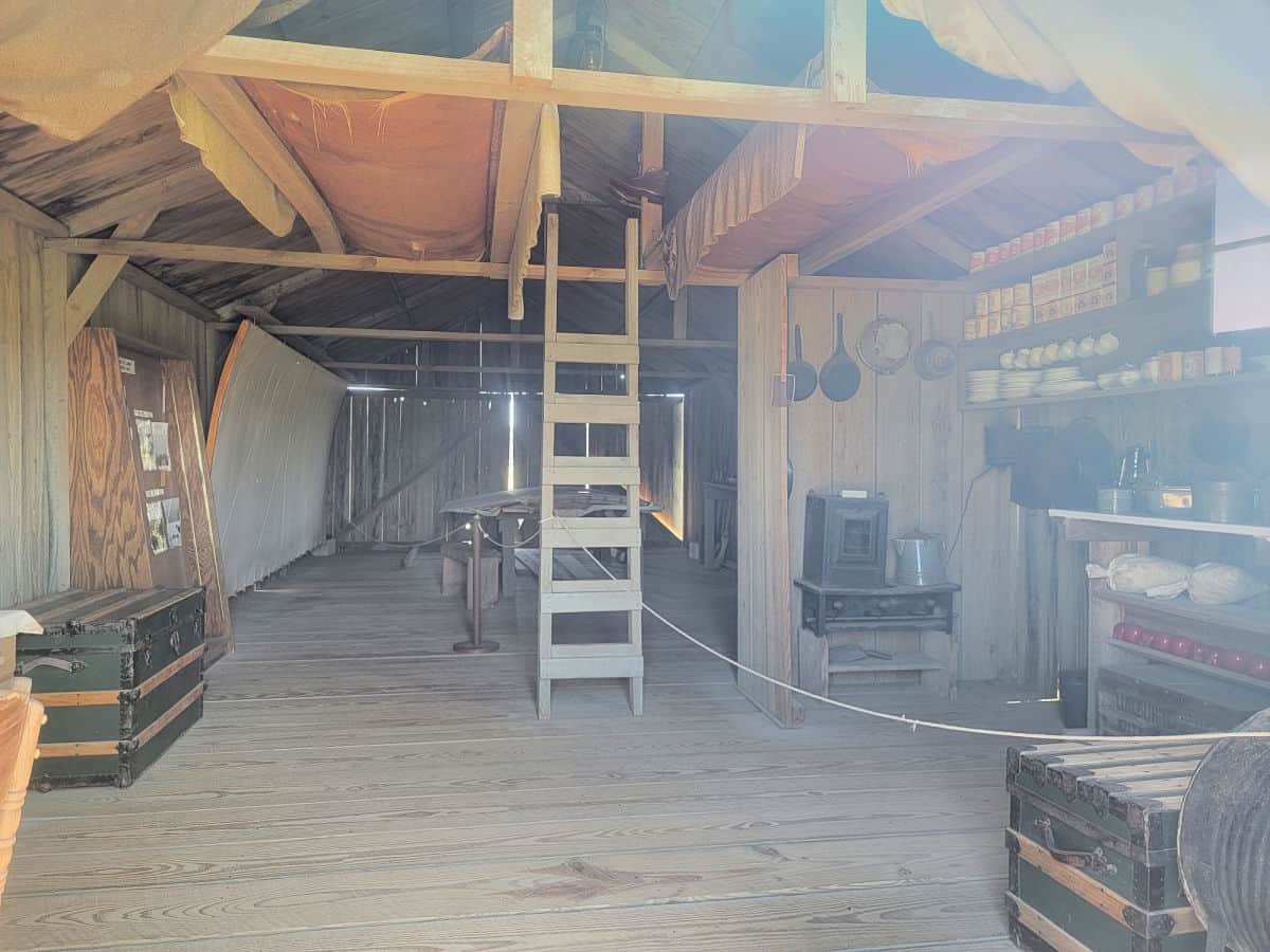 Inside of the wright brothers reconstructed 1903 camp buildings showing a ladder, pots and pans, beds