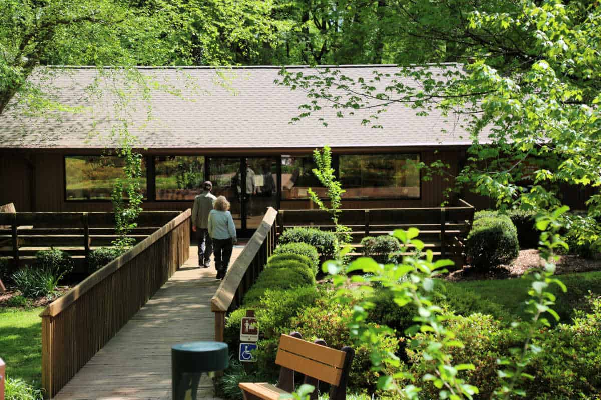 A couple walking over a bridge to the visitor center surrounded by greenery