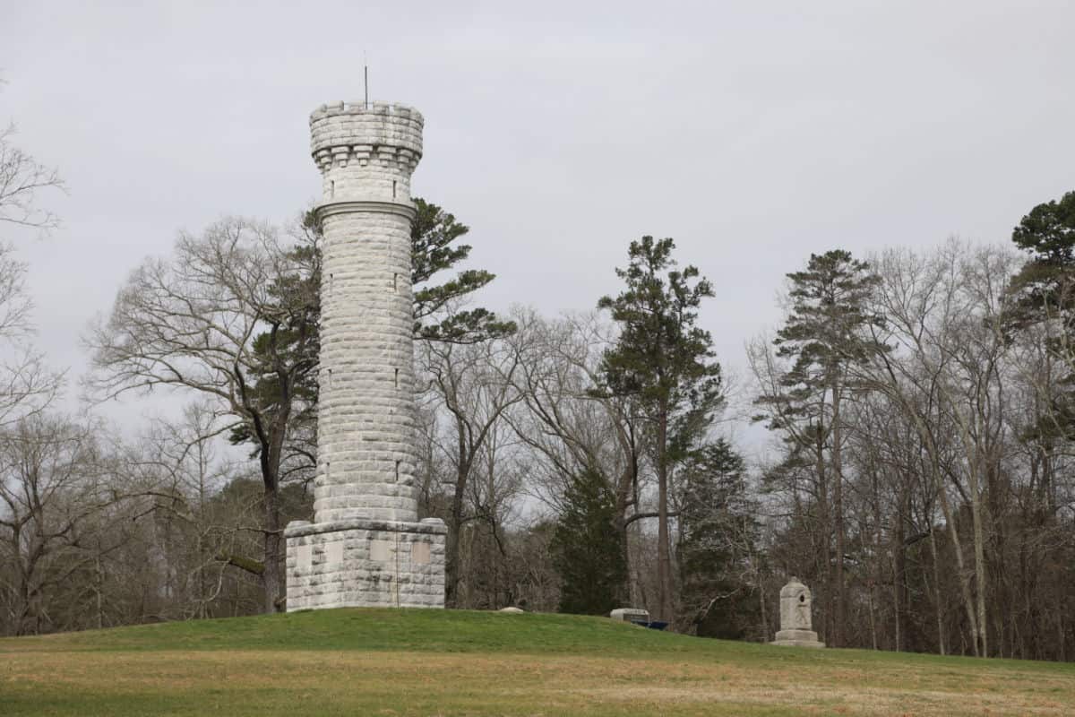 Large Monument in a grassy field with trees in the background 