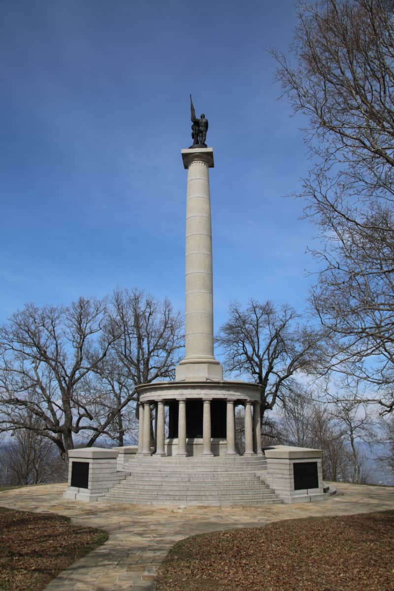 Large memorial with statue on top surrounded by trees