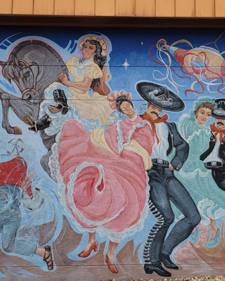 Painted mural with dancers, a horse, pinata