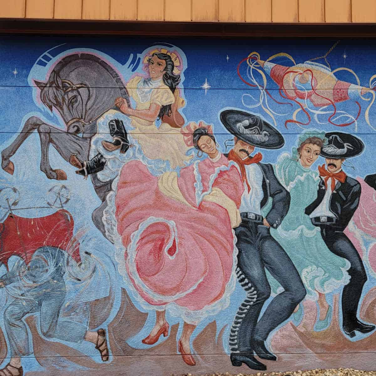 Painted mural with dancers, a horse, pinata