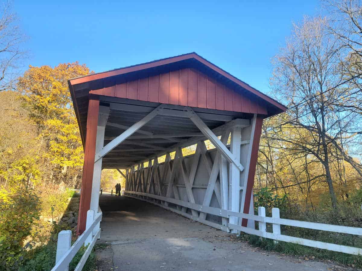 Red roofed covered bridge with a paved trail through it