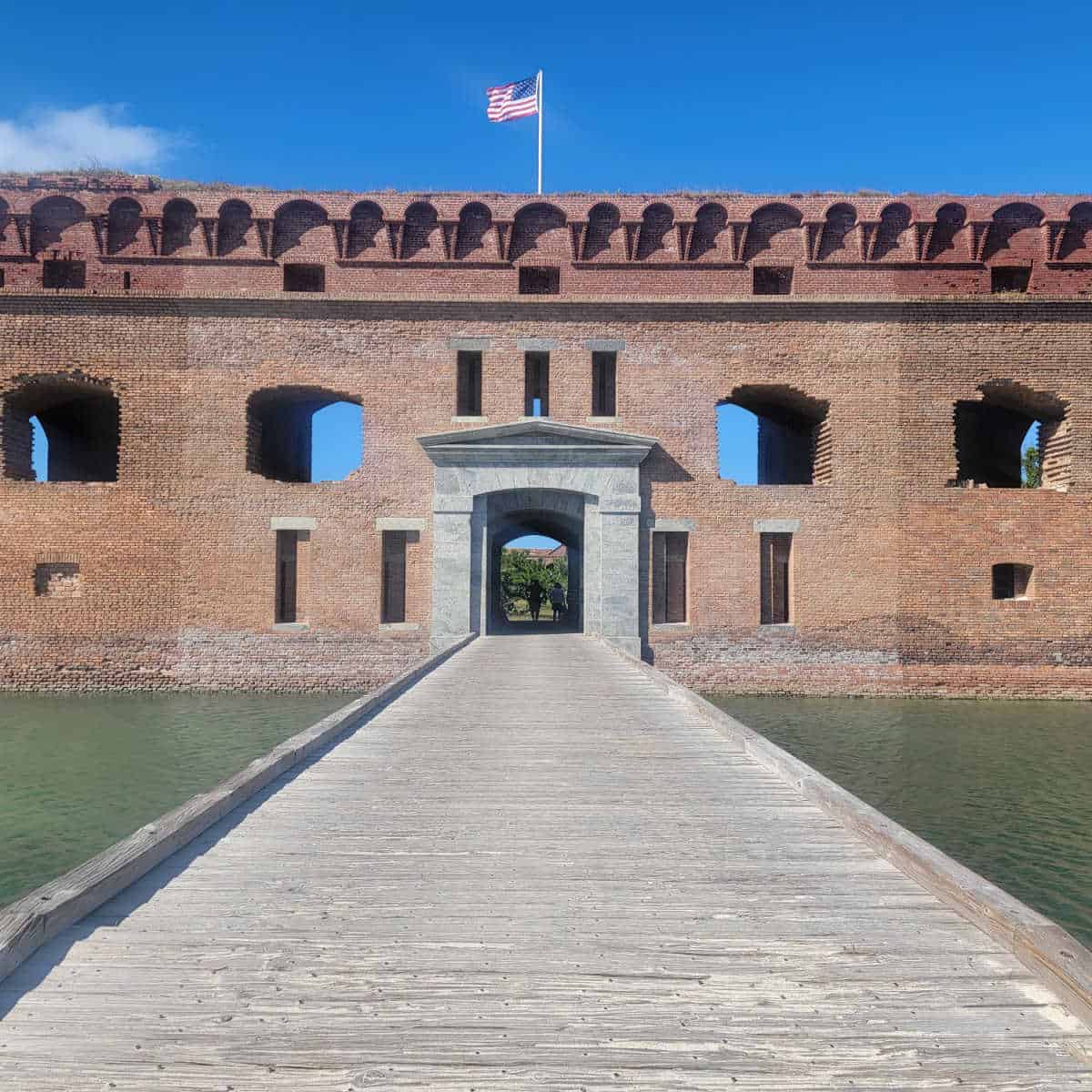 Wooden bridge entering into Fort Jefferson brick fort with an American Flag on top