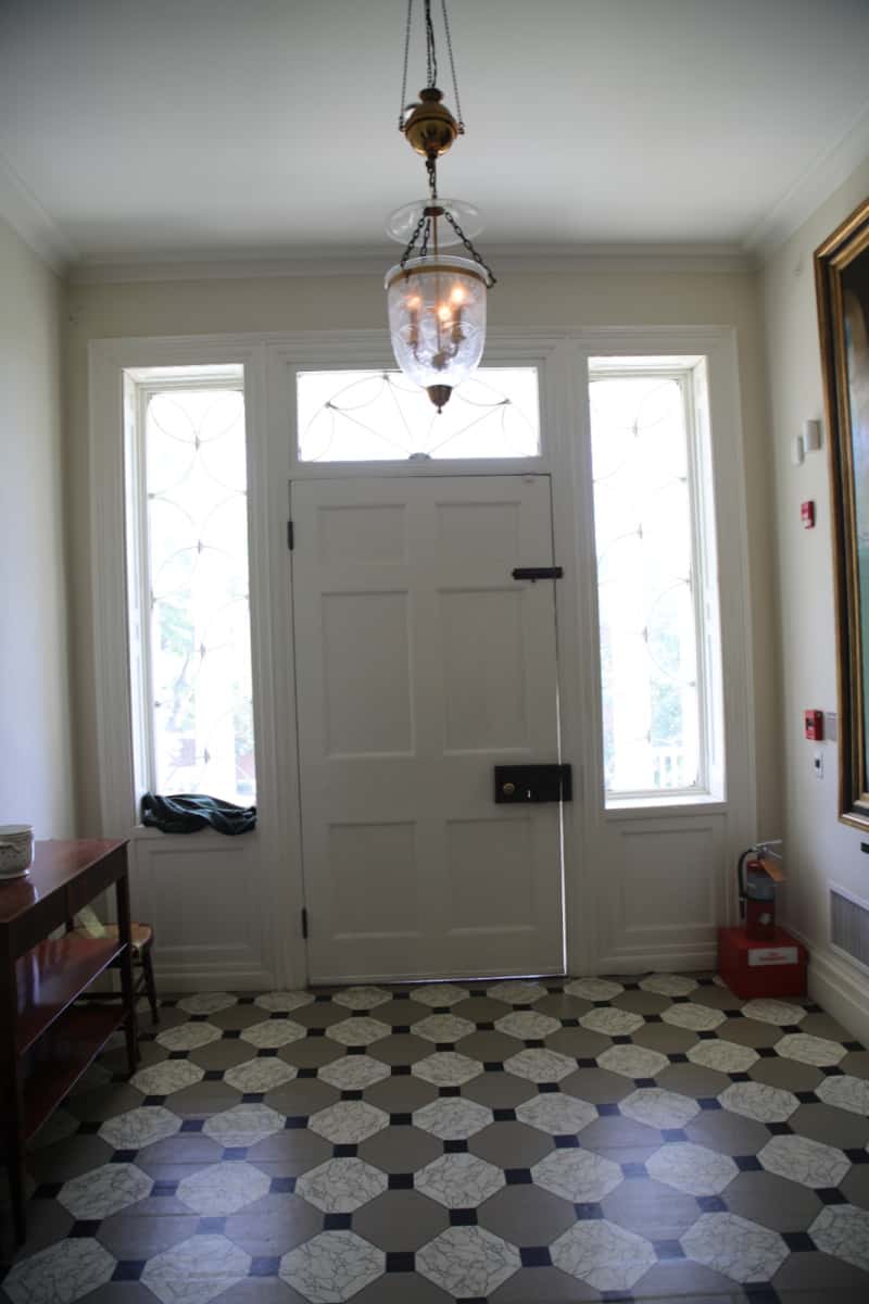 White entrance door, historic tiles, and glass chandelier