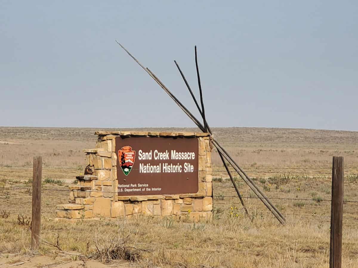 Sand Creek Massacre national historic site entrance sign with teepee poles leaning against it